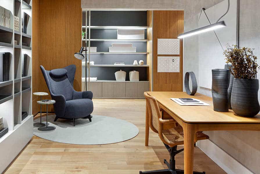 espaço para home office com mesa, cadeira, poltrona e estantes