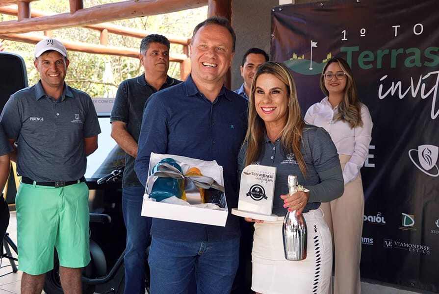 mulher e homem recebem premio do torneio de golfe