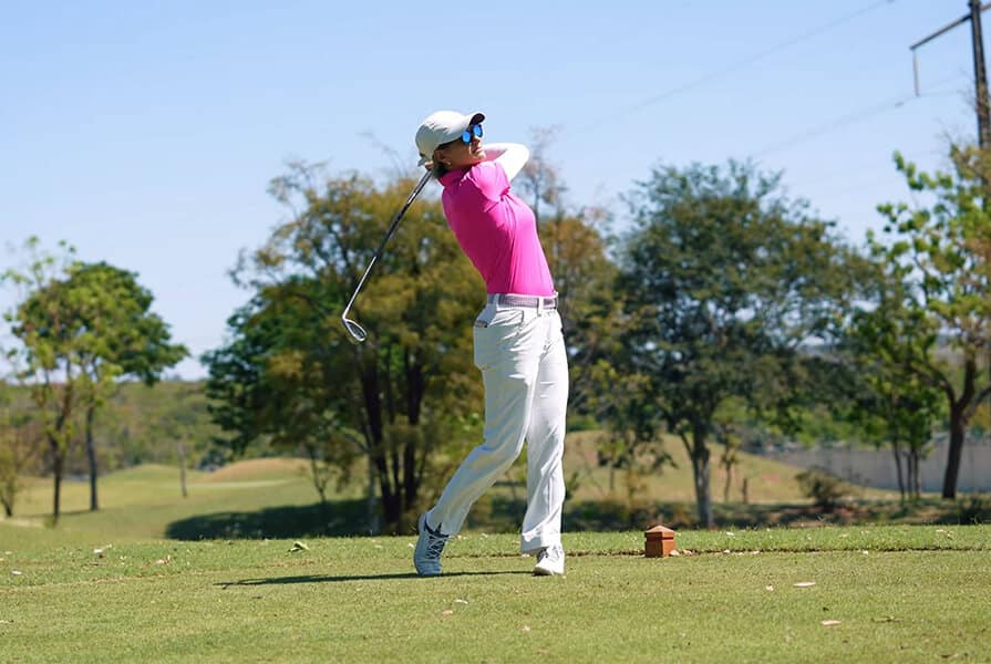 mulher de camisa rosa joga golfe