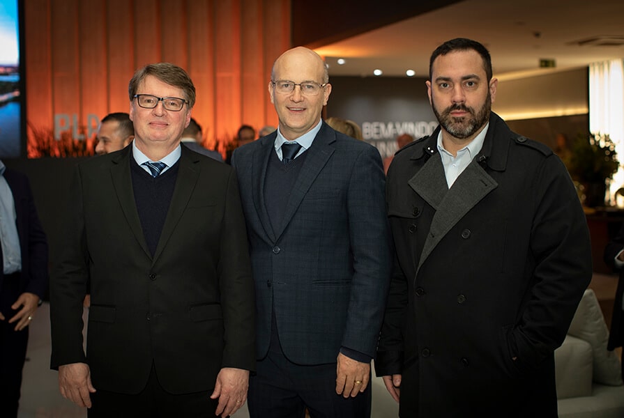 tres homens de terno em evento