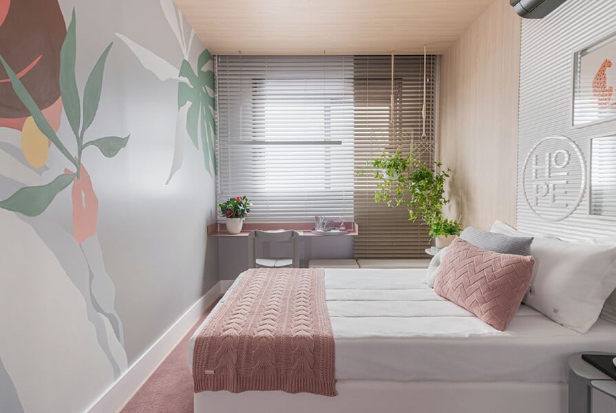 quarto com pinturas na parede e cama rosa, cores que acalmam