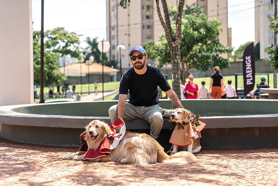 homem com dois cachorros vestidos de natal