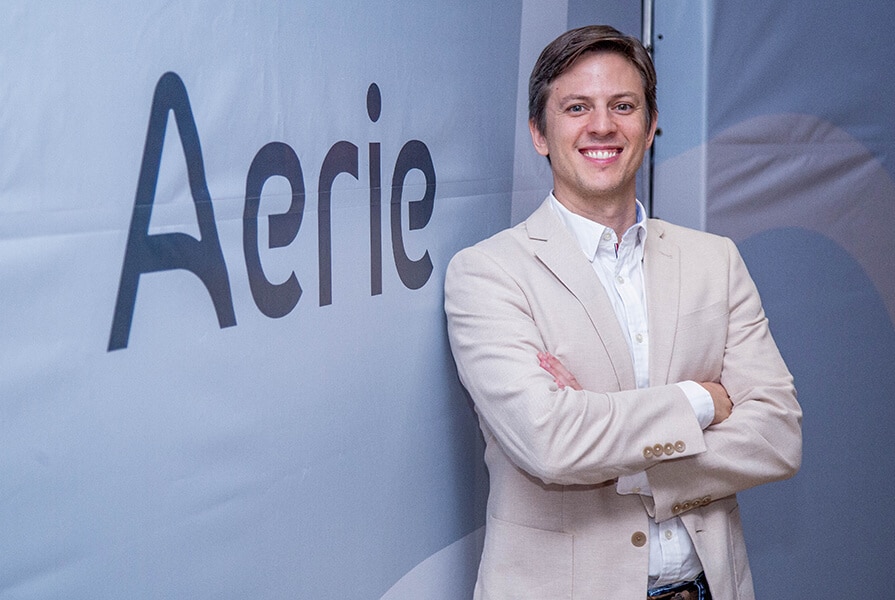 homem sorrindo de braços cruzados em evento aerie