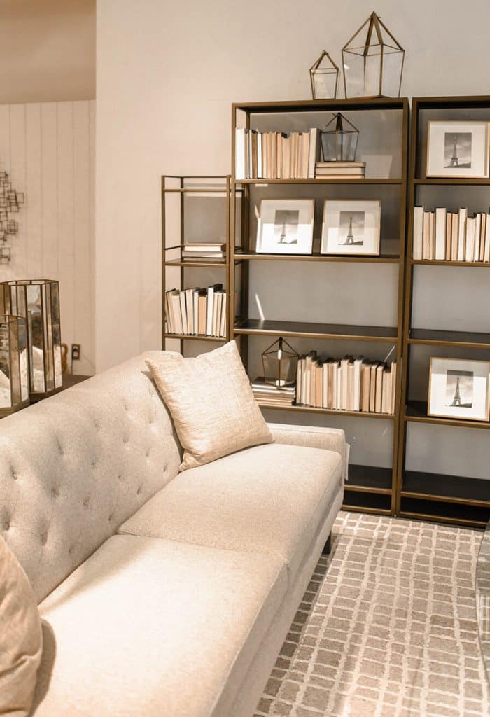 Sala com sofá off white e estante minimalista com livros