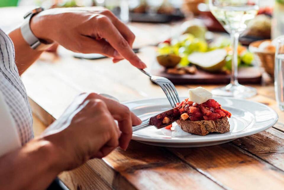 bruschetta servida no prato, sendo cortada por uma pessoa