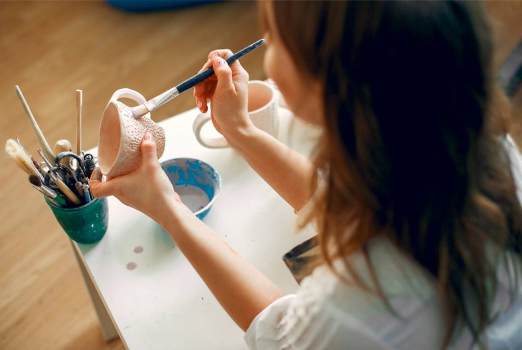 mulher pintando xícara de cerâmica