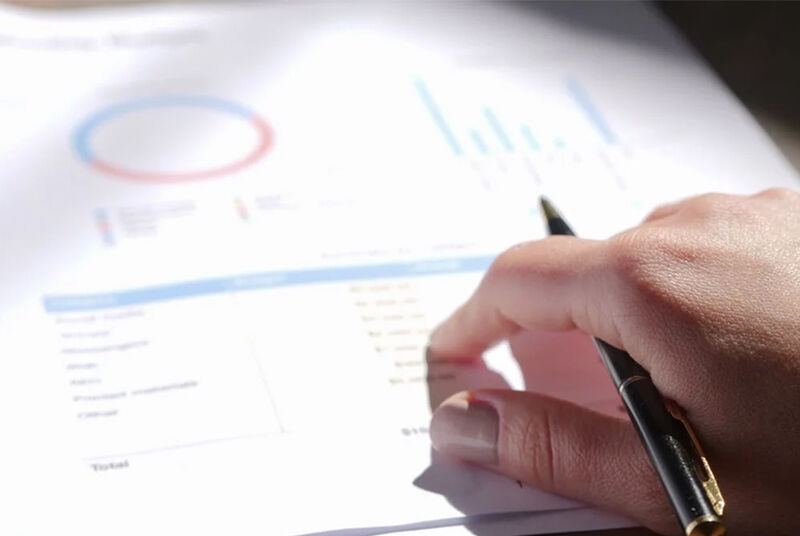 Mão analisando gráfico em relatório financeiro