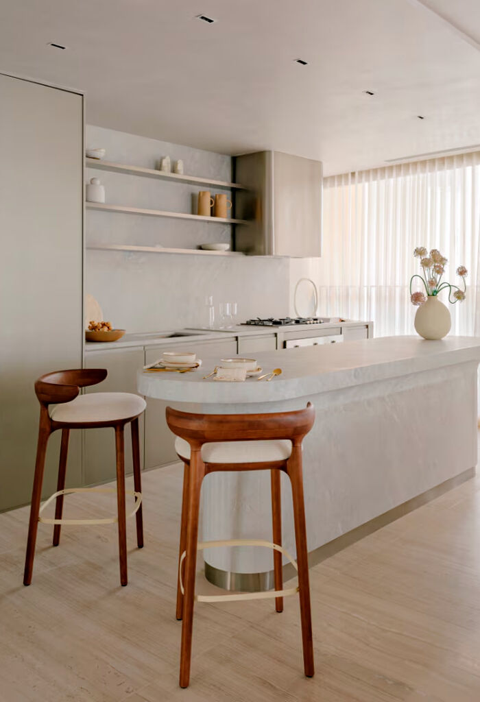 Cozinha moderna com bancadas claras e banquetas de madeira