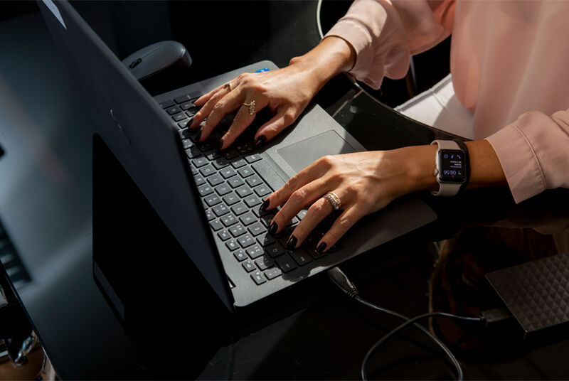Mãos digitando em notebook moderno com smartwatch