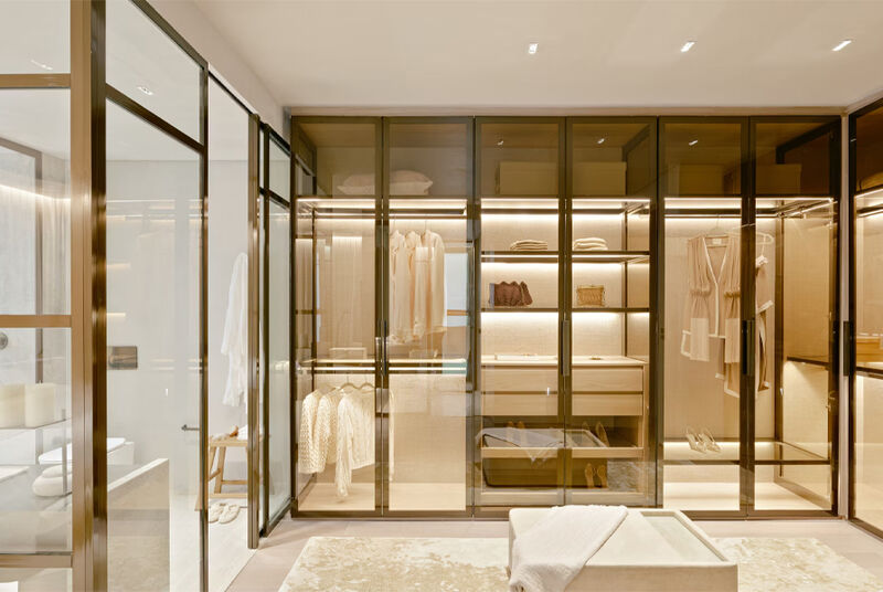 Closet moderno com armários de vidro e iluminação suave